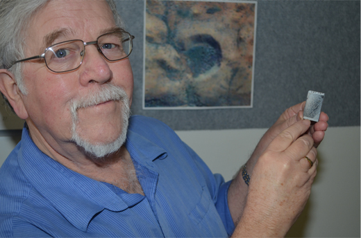 Dr Arthur Hickman and a slide from Marble Bar showing a band of asteroid impact spherules that can be seen clearly under a microscope.